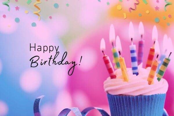 A cupcake with candles and the words 'Happy Birthday' on a colorful confetti filled background.